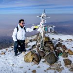 A mountaineer at the summit in the snowy Andes, displaying adventure and freedom in Peru.