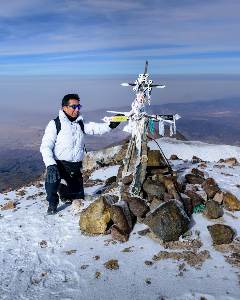 A mountaineer at the summit in the snowy Andes, displaying adventure and freedom in Peru.